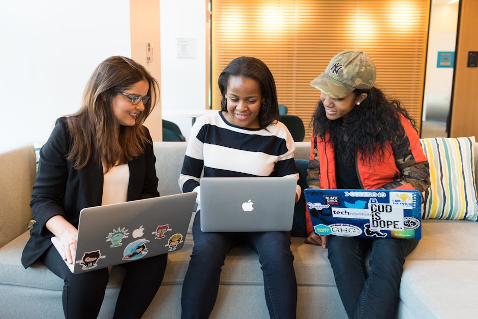 Three women working together on laptops in a casual office setting, emphasizing teamwork and collaboration